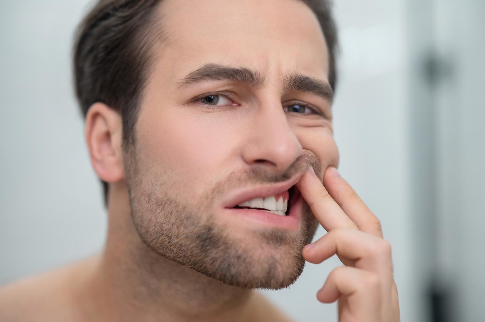 A man holding his cheek in discomfort from gum pain